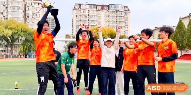 Excited students celebrate a victory with their arms raised on the sports field at the Attached Senior School Of Shandong Normal University.