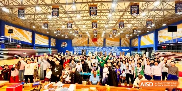 A large crowd of students gathers in an indoor gymnasium for a school presentation at the Attached Senior School Of Shandong Normal University.