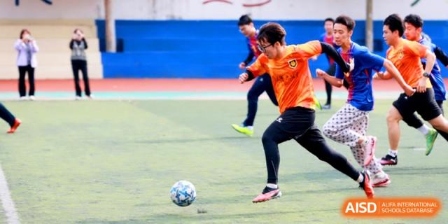 A player in an orange jersey dribbles the ball down the field during a game at the Attached Senior School Of Shandong Normal University.