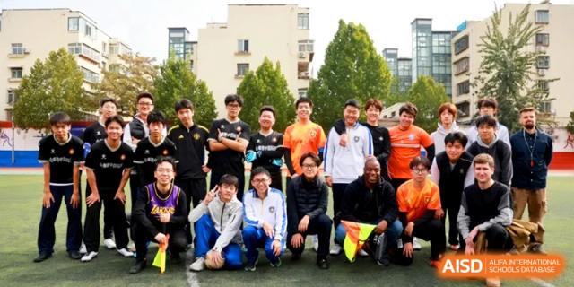 A diverse group of students and coaches gather for a commemorative team photo at the Attached Senior School Of Shandong Normal University.