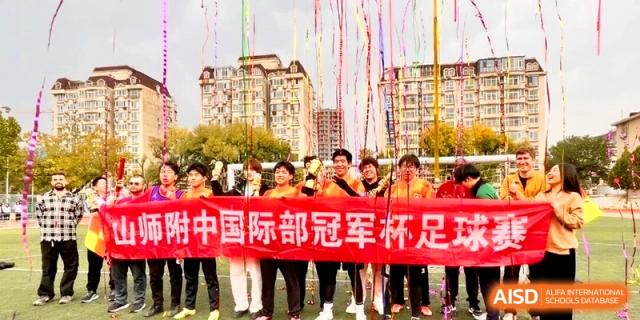 Students hold a large red banner to celebrate a championship win on the field at the Attached Senior School Of Shandong Normal University.