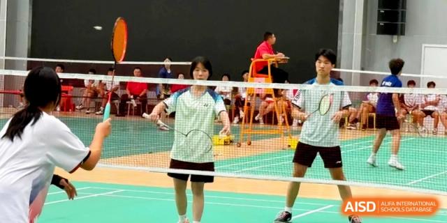 Students play a competitive game of badminton in the indoor school sports hall at the Attached Senior School Of Shandong Normal University.
