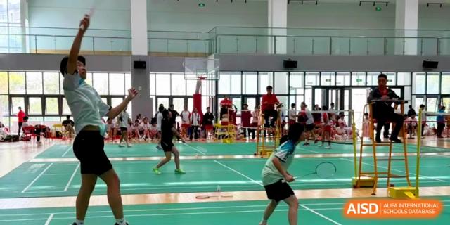 A view of students playing badminton on several courts in the school gymnasium at the Attached Senior School Of Shandong Normal University.