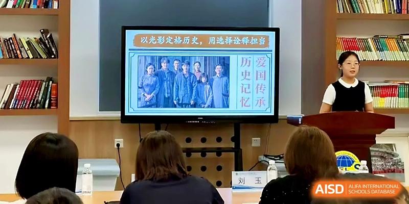 A television screen shows a group photo of students during a historical or cultural presentation at Tianjin Foreign Languages School.