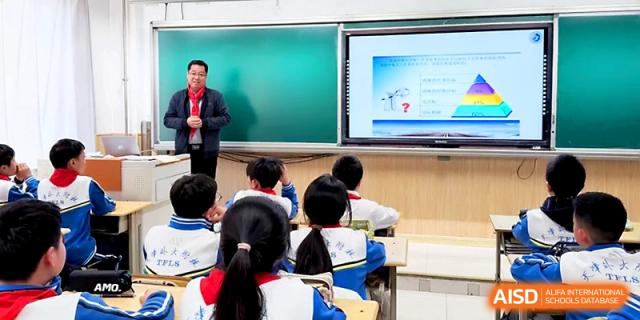 A male teacher stands before a class of students while using an interactive digital whiteboard at Tianjin Foreign Languages School.