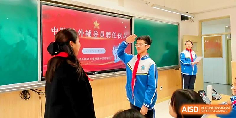 A student in a blue and white uniform salutes a teacher during a formal classroom ceremony at Tianjin Foreign Languages School.