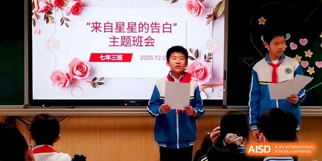 A student stands and reads from a script in front of a digital screen during a class presentation at Tianjin Foreign Languages School.