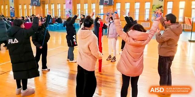 Students participate in a fun physical activity involving colorful poles in a school gymnasium at Tianjin Foreign Languages School.