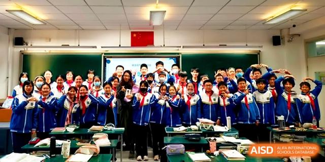 A wide shot of a classroom filled with students posing together for a commemorative group picture at Tianjin Foreign Languages School.