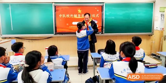 A student ties a red scarf for a male teacher while classmates watch from their desks at Tianjin Foreign Languages School.