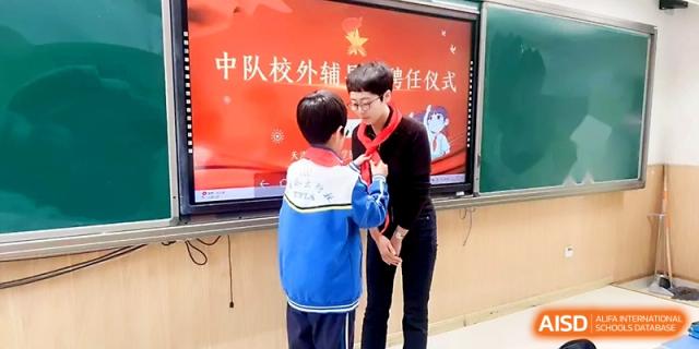 A young student ties a red scarf for a teacher during a formal induction ceremony at Tianjin Foreign Languages School.