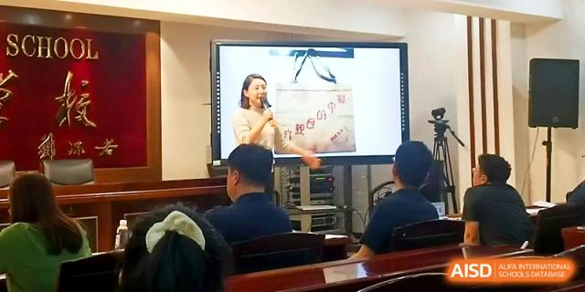 A teacher uses an interactive whiteboard to show educational illustrations to a group of attendees at Tianjin Foreign Languages School.