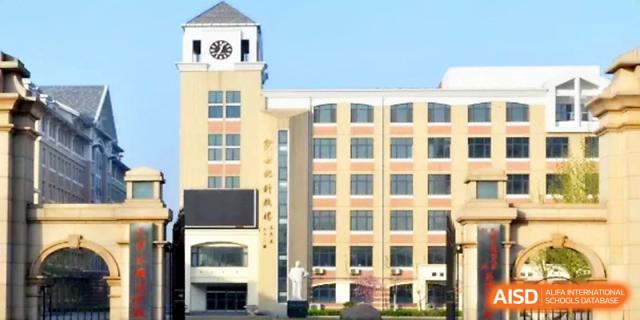 A bright exterior shot of the campus clock tower and main academic building under a blue sky at Tianjin Foreign Languages School.