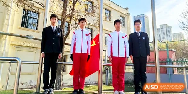 Student representatives in formal and athletic attire stand before the national flag during a campus event at Tianjin Foreign Languages School.