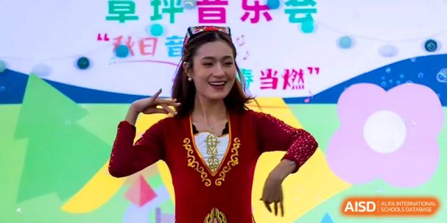 A student in a traditional red costume performs a cultural dance on a colorful stage at Tianjin Foreign Languages School.