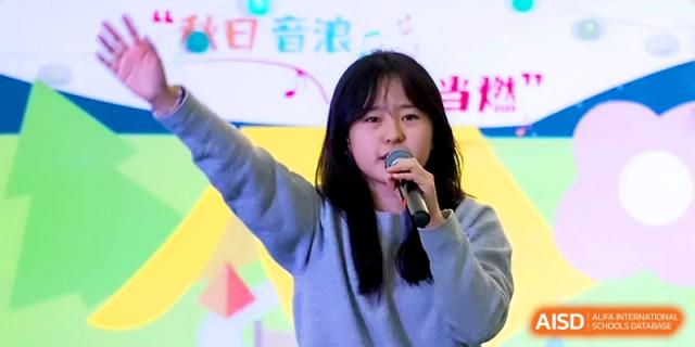 A female student sings with passion into a microphone during an outdoor music festival event at Tianjin Foreign Languages School.