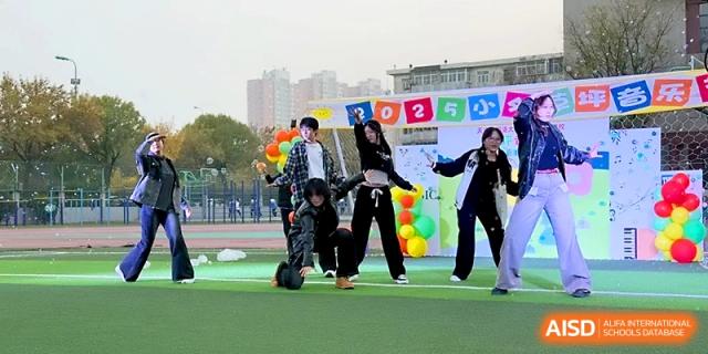 A group of students performs a synchronized modern dance routine on the green athletic field at Tianjin Foreign Languages School.