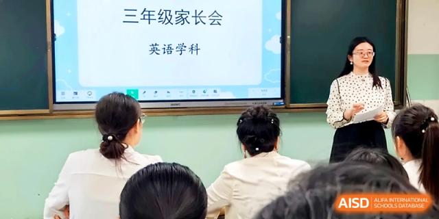 A presentation slide for a third-grade parents' meeting is displayed on a screen in a classroom at Urumqi Bayi High School.