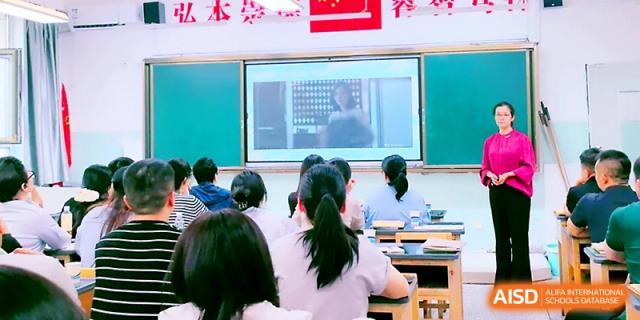 Students sit at their desks while watching an educational presentation on a screen at the front of Urumqi Bayi High School.
