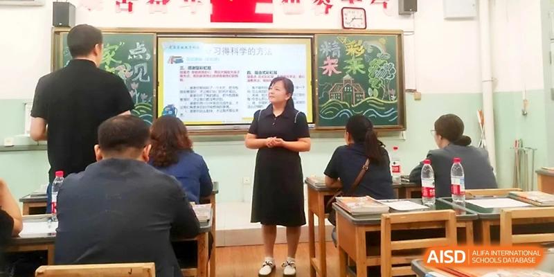 A female teacher stands before a classroom of students to deliver a presentation or lecture at Urumqi Bayi High School.