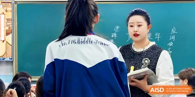 A teacher assists a student wearing a school jacket during a classroom activity at Urumqi Bayi High School.