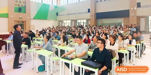 A large group of parents or students sits at long tables for a formal school meeting at Urumqi Bayi High School.