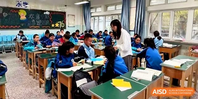 A teacher walks through a classroom of students working on assignments at their desks in Urumqi Bayi High School.