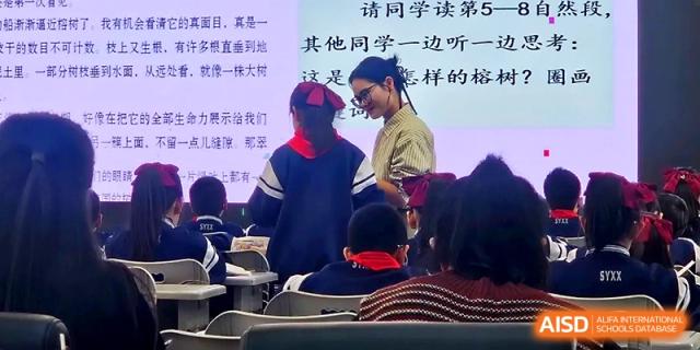 A teacher stands at the front of the room during a multimedia presentation for a class at Urumqi Bayi High School.