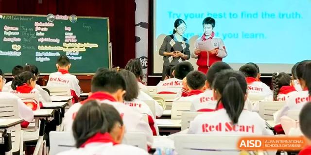 Students stand at the front of a classroom to lead a presentation or group activity at Urumqi Bayi High School.
