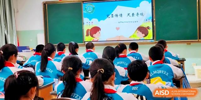 A classroom of students in blue uniforms faces the front while a teacher leads a lesson with a digital board at Urumqi Bayi High School.