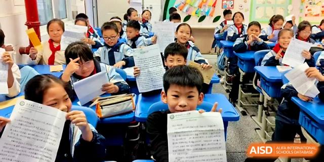 Enthusiastic students hold up their completed assignments or papers while sitting at their desks at Urumqi Bayi High School.