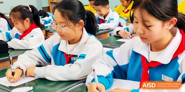 A student focuses on her writing while working diligently at her desk during a lesson at Urumqi Bayi High School.