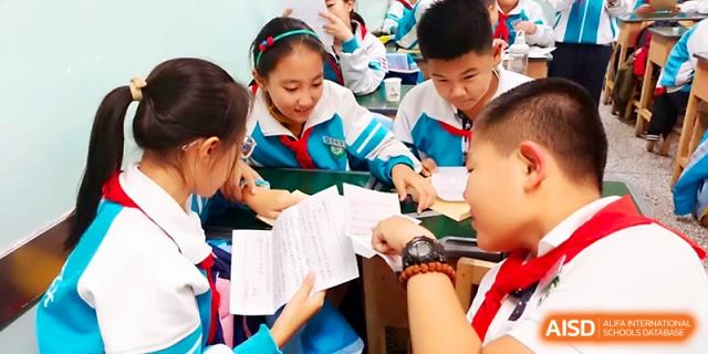 A group of students gather around a desk to collaborate on a hands-on learning project at Urumqi Bayi High School.
