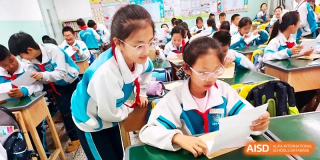 Two students work together closely to review their lesson materials in a bright classroom at Urumqi Bayi High School.