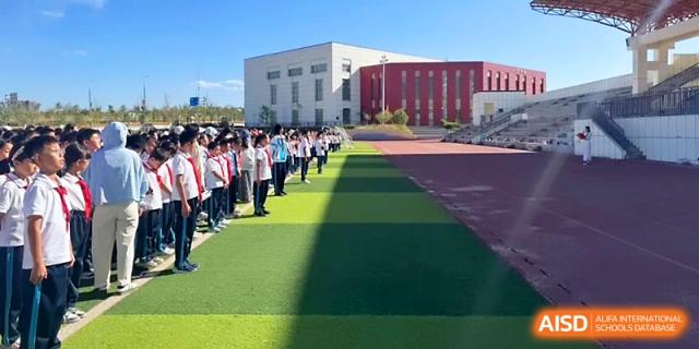 Students line up on the green synthetic turf of the school's large outdoor sports field at Urumqi Bayi High School.