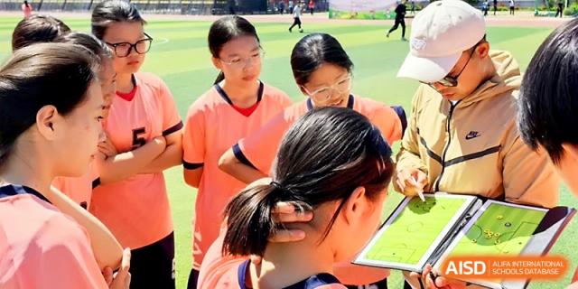 A group of students in orange athletic jerseys huddle together to discuss their strategy at Urumqi Bayi High School.