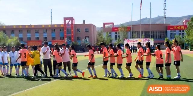 Students in pink athletic shirts participate in a coordinated group exercise on the field at Urumqi Bayi High School.