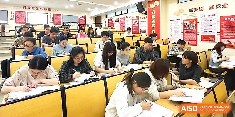 Students are seated in a tiered lecture hall, diligently taking notes during a focused academic session at Wuhan Guanggu Future School.