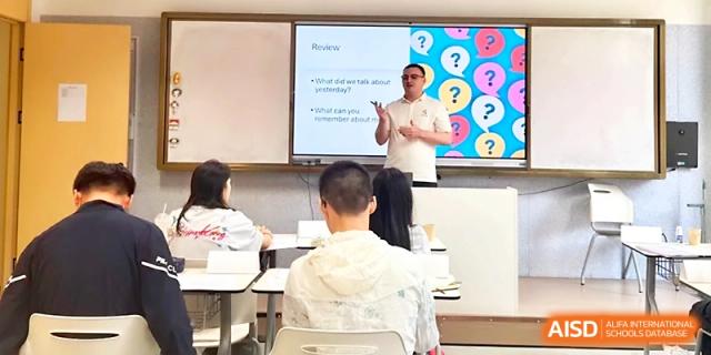 An instructor gives a presentation using a digital screen to a class of attentive seated students at Wuhan Guanggu Future School.