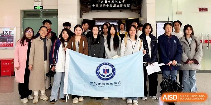 A group of students stands together holding a large light blue school flag in front of a building at Wuhan Guanggu Future School.