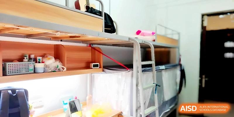 A clean and organized student dormitory room features a sturdy metal bunk bed and personal desk at Wuhan Guanggu Future School.