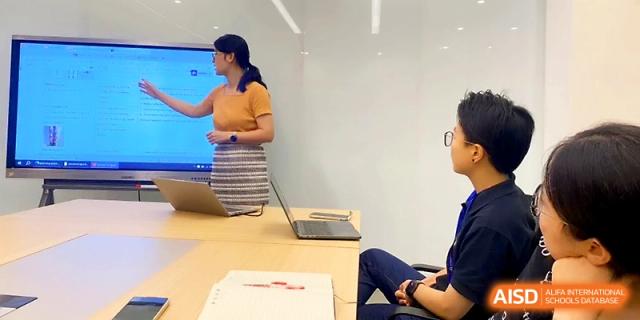 A teacher presents a lesson on a screen to a student in a modern, well-equipped office or study space at Wuhan Guanggu Future School.