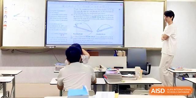 A large digital screen displays a detailed textbook page to a classroom of seated students during a lecture at Wuhan Guanggu Future School.