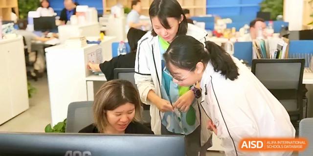 Two teachers lean over a computer screen, collaborating and guiding a student through a digital task at Wuhan Guanggu Future School.