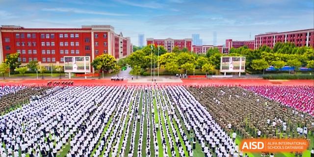 An aerial view shows a massive assembly of students in uniform standing in perfect rows on a large field at Wuhan Guanggu Future School.
