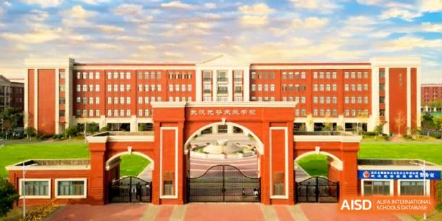 A wide shot captures the grand red-and-white entrance gate and main buildings of the campus at Wuhan Guanggu Future School.