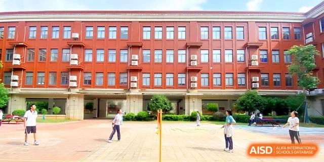 Two students participate in an outdoor activity on a paved courtyard in front of a red brick building at Wuhan Guanggu Future School.