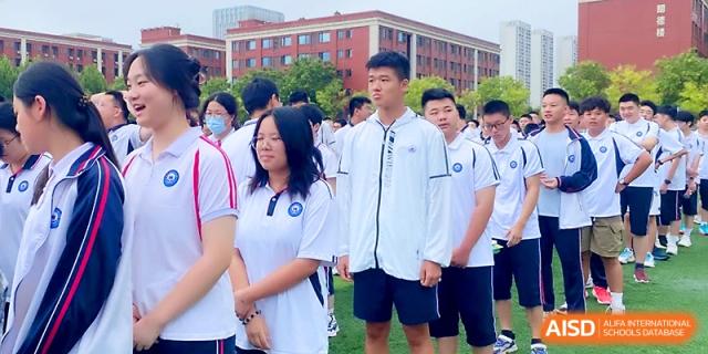 Students in white and blue uniforms stand in an organized group outdoors on a bright day at Wuhan Guanggu Future School.