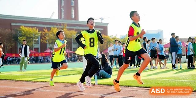 Young students in neon yellow vests compete in a running race on a sunny outdoor track at Wuhan Guanggu Future School.