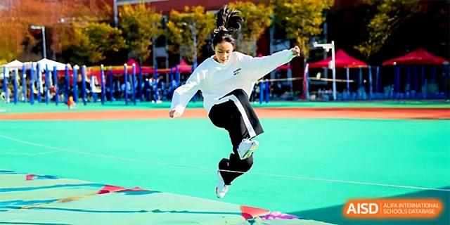 A female student performs a high-energy jump during a physical education class on the outdoor track at Wuhan Guanggu Future School.